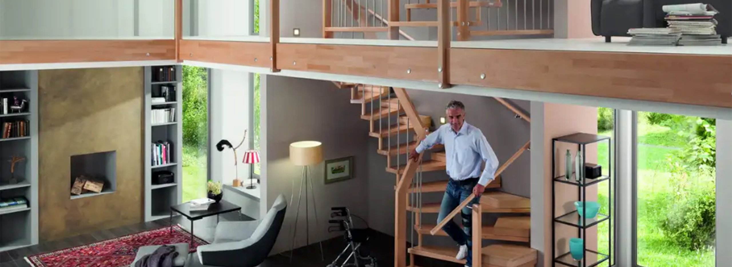Ein modern eingerichtetes Wohnzimmer mit hoher Decke und großen Fensterfronten. Eine helle Holztreppe mit Handlauf führt in das obere Stockwerk. Symbolbild für barrierefreie Treppen.