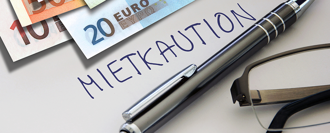 Ein Zettel mit dem Wort „Mietkaution“, dazu Geldscheine, Stift und Brille – es geht um finanzielle Absicherung bei Mietbeginn. Symbolbild für: Mietkaution.