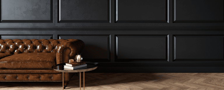 Luxuriös eingerichteter Raum mit einem klassischen Chesterfield-Ledersofa in Braun vor einer eleganten schwarzen Wand mit stilvollen Wandpaneelen schaffen eine gehobene Atmosphäre. Symbolbild für Exklusivität, Private Banking und hochwertige Finanzberatung.